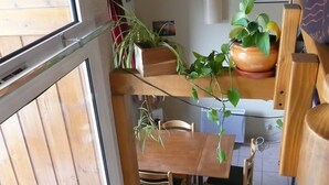 A wooden dining area with a table and chairs, a hanging plant, and a tiled floor. - Serre-chevalier 1200, briançon, light runway, comfort, amenities  (Briançon)