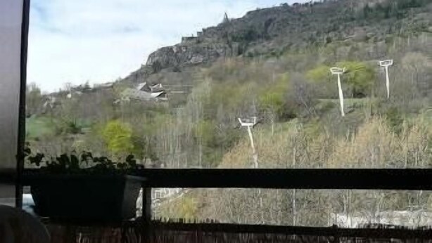 A balcony with a view of a hilly landscape, a table, and a chair. - Serre-chevalier 1200, briançon, light runway, comfort, amenities  (Briançon)