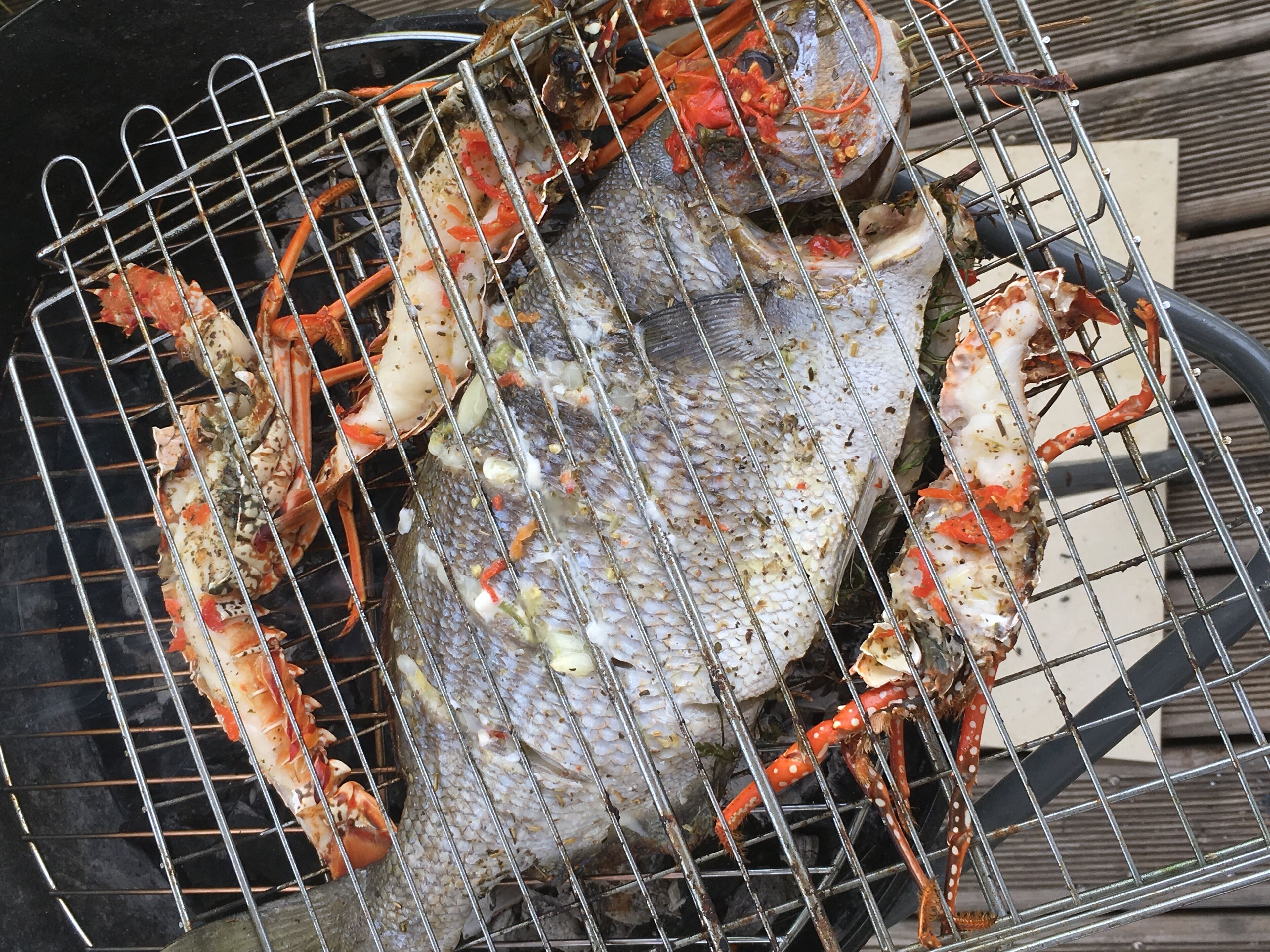 Una parrilla con un pescado grande y varios cangrejos.