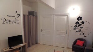 Ett vardagsrum med en tv, två röda fåtöljer, en soffa och en vägg dekorerad med ett blommönstrat motiv.