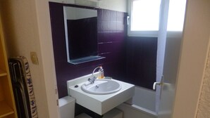 Un baño pequeño con lavamanos blanco, un espejo y un inodoro.