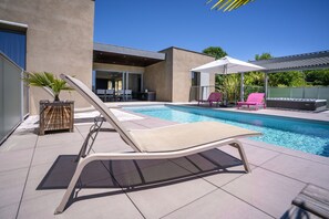 A modern outdoor pool area with lounge chairs and umbrellas. - Villa Calmont : Oasis of Serenity in Aveyron with Private Pool and Jacuzzi (Espalion)
