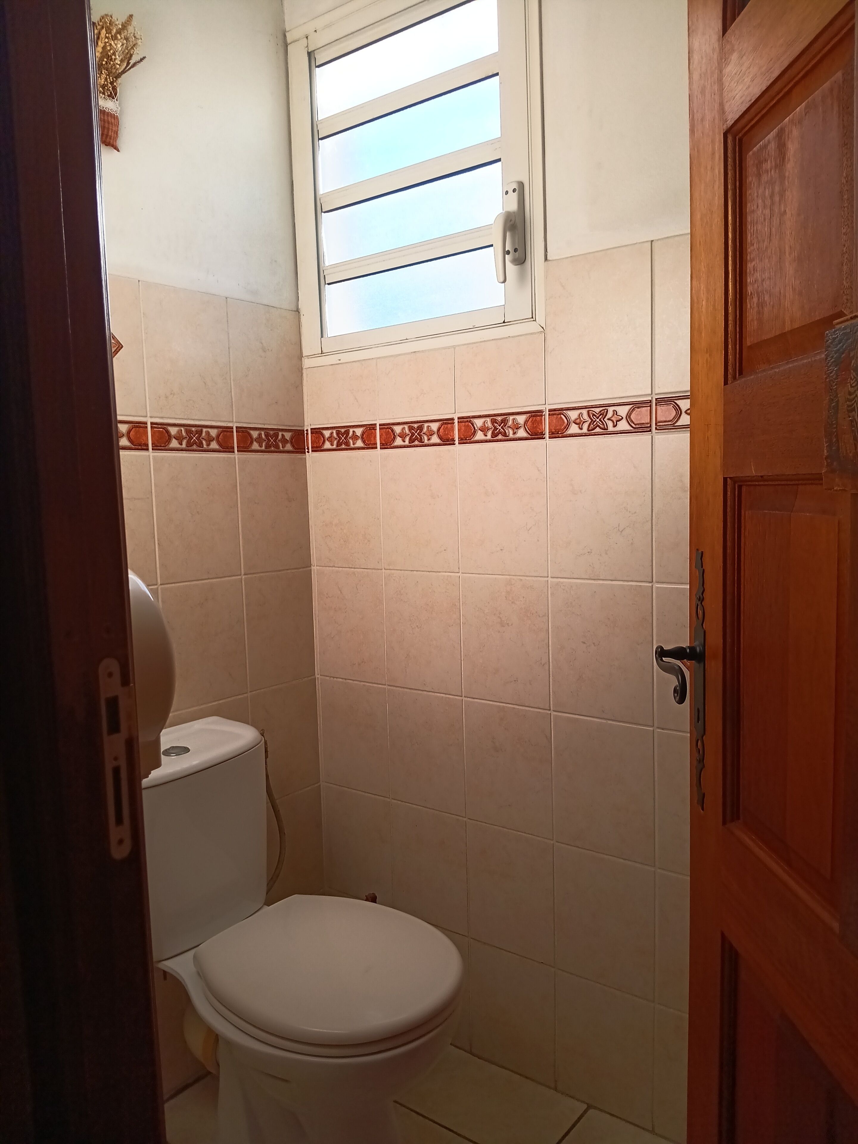 A small bathroom with a toilet, a window, and a door.