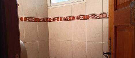 A small bathroom with a toilet, a window, and a door.