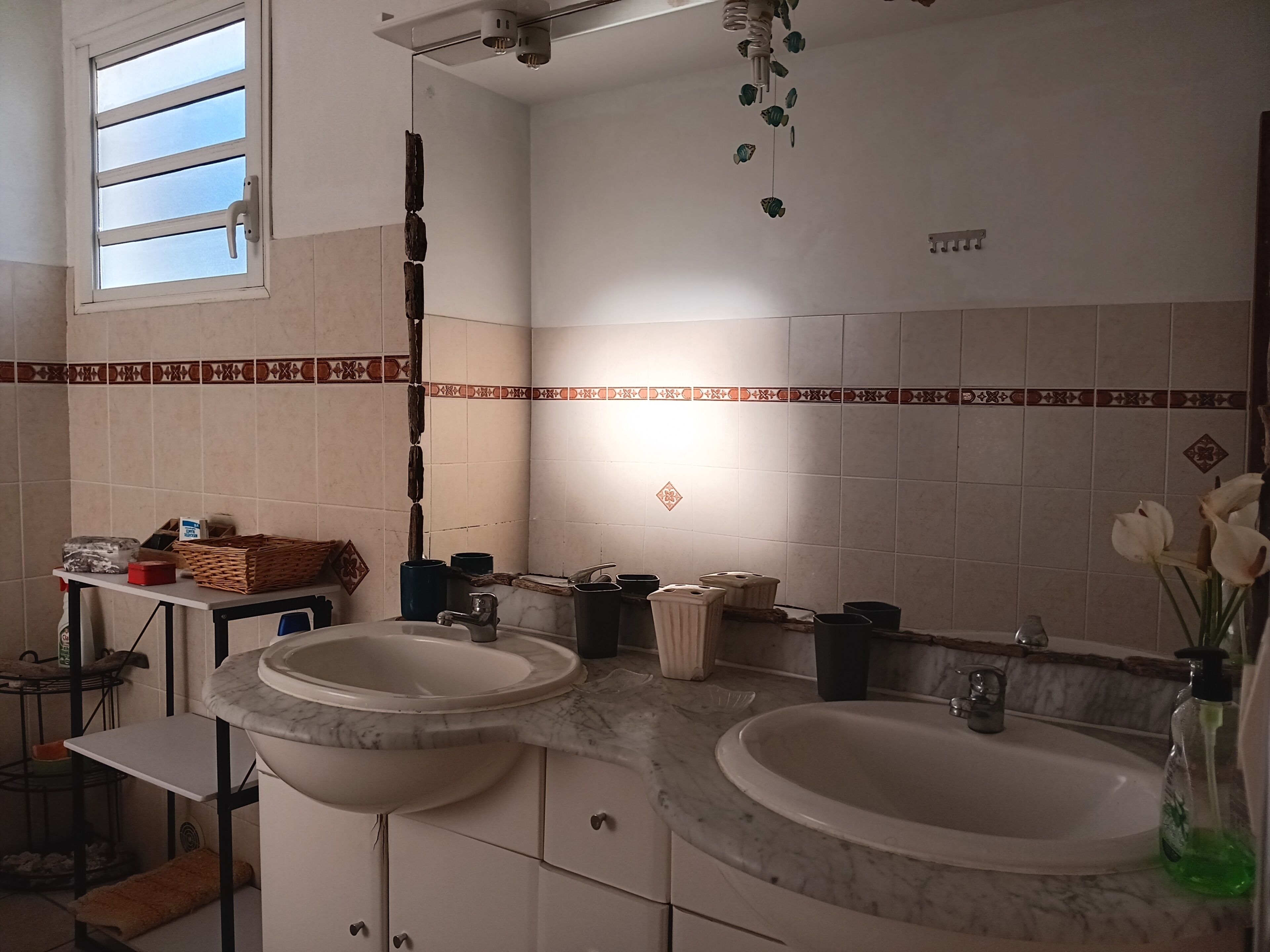 A bathroom with two sinks, a mirror, a ceiling fan, and a window.