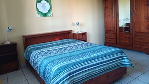 Ein Schlafzimmer mit einem Bett, einem Holzschrank, Nachttischlampen und einem Wandbild.