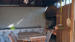 Eine Terrasse im Freien mit einem runden Holztisch und Stühlen, einer Ziegelwand und einer hängenden Leuchte.