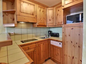 Una cocina con armarios de madera, un lavamanos, una cafetera y un lavavajillas.