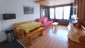 Um quarto aconchegante com um banco de madeira, um sofá vermelho, uma mesinha e um radiador.