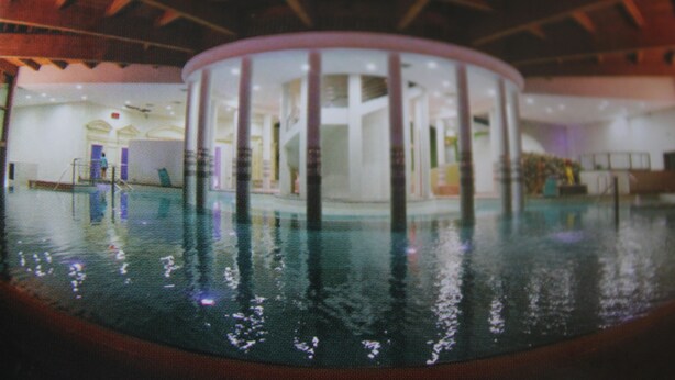 An indoor swimming pool with a circular viewing area, surrounded by a wooden deck and a covered seating area. - Serre Chevalier Le Mônétier Les Bains F3 Magnifique vue face aux Ecrins (Le Monêtier-Les-Bains)