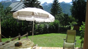 A wooden deck with a table and chairs, an umbrella, and a chair. - Serre Chevalier Le Mônétier Les Bains F3 Magnifique vue face aux Ecrins (Le Monêtier-Les-Bains)