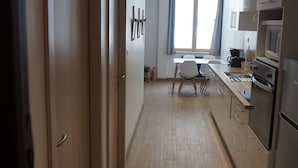 Une cuisine moderne avec des meubles en bois, un four encastré et un coin repas comprenant une table et des chaises.