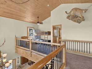 A multi-level room with a bunk bed, a ceiling fan, and a mounted animal head.