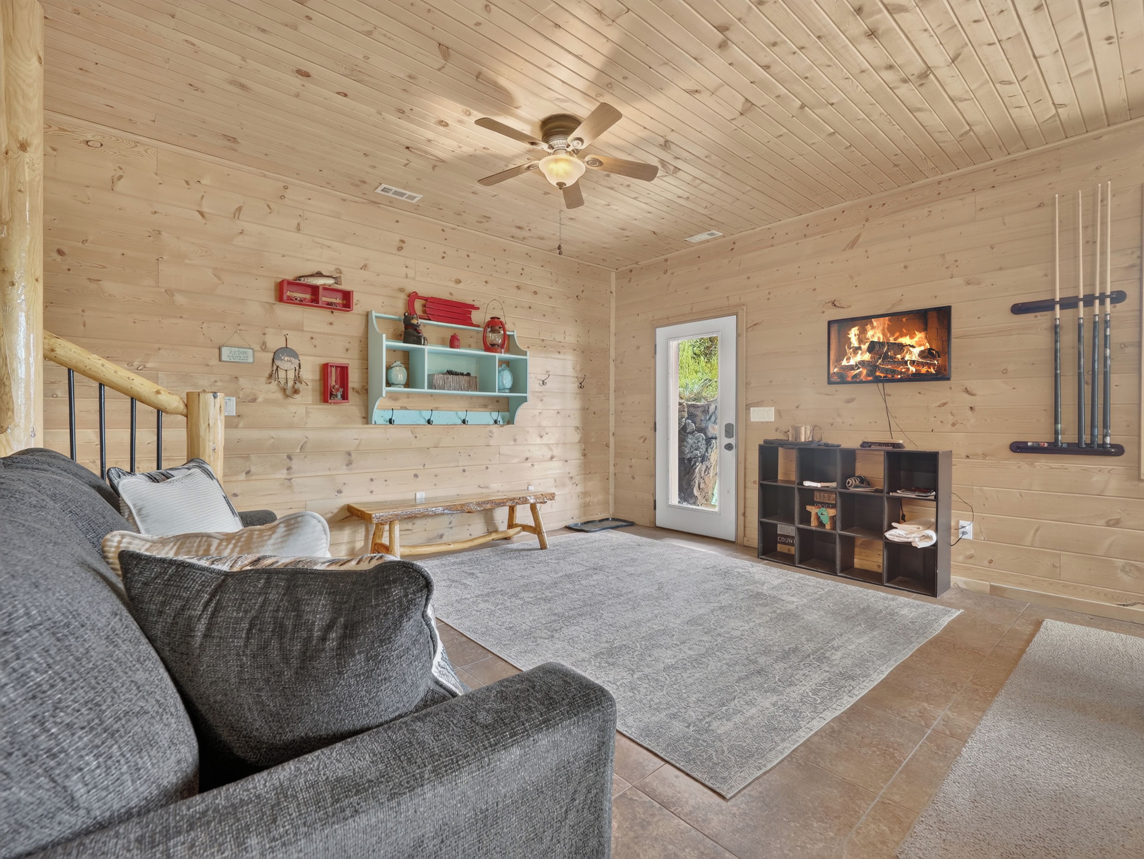 A cozy room with a wooden ceiling, a bench, a sofa, a fireplace, and a television.
