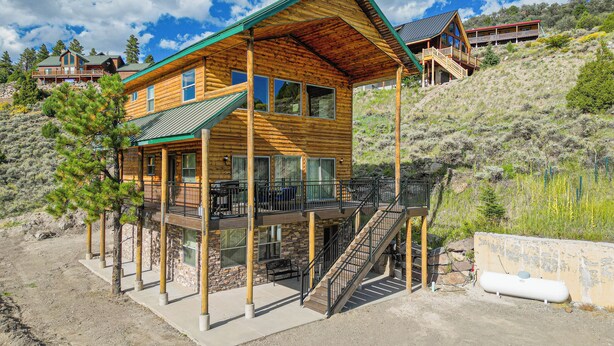 A wooden cabin with a balcony, a staircase, and a view of the surrounding landscape.