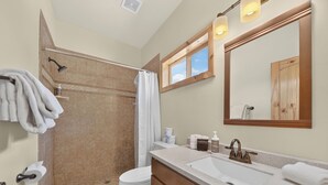 A bathroom with a shower, toilet, sink, and vanity.