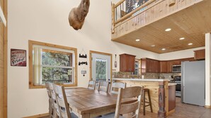 A spacious kitchen with wooden cabinets, a stainless steel refrigerator, and a dining area with a large wooden table and chairs.