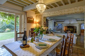 A dining area with a table set for four, a chandelier, and a fireplace in the background. - Mas de la Treille - pool - garden (Les Baux-De-Provence)