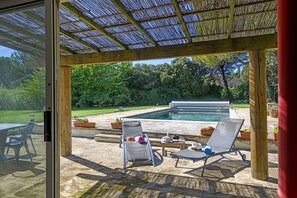 A covered outdoor area with a pool, lounge chairs, and a table. - Mas de la Treille - pool - garden (Les Baux-De-Provence)