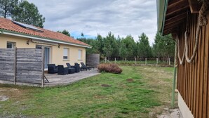 Una casa con techo de tejas, terraza de madera y mobiliario exterior.