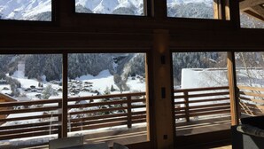 A room with large windows offering views of snow-covered mountains and a village below. - New chalet exceptional rated 5 *, conveniently located only Contamines (Les Contamines-Montjoie)