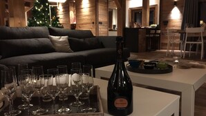 A cozy living room with a dark-colored sofa, a white coffee table, and a bottle of Dom Ruinart champagne. - New chalet exceptional rated 5 *, conveniently located only Contamines (Les Contamines-Montjoie)
