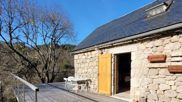 A stone building with a wooden deck and a door leading inside. - L'Ostel Aveyronnais (golinhac)