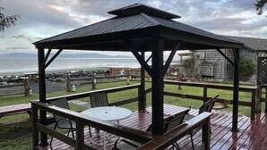 Una terraza de madera con un mirador, una mesa redonda y sillas.