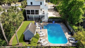 Una casa de dos pisos con piscina, un porche cubierto y un pequeño cobertizo.