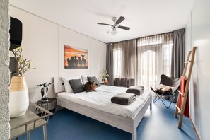 A modern bedroom with a bed, a standing fan, a chair, a small table, and a painting on the wall. - Unwind in this modern villa in Friesland (Rijs)