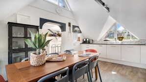 Una cocina moderna con una mesa de madera, sillas y una planta en maceta.
