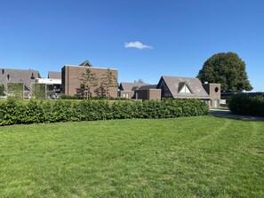 A modern building complex with multiple brick buildings, a well-maintained lawn, and a large tree in the background. - Unwind in this modern villa in Friesland (Rijs)