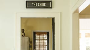 A doorway leading to a kitchen with a refrigerator, a door with a window, and a sign above reading "THE SHIRE".