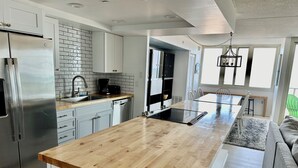 Eine moderne Küche mit Holzarbeitsplatte, Edelstahlgeräten und einem Essbereich mit Tisch und Stühlen.