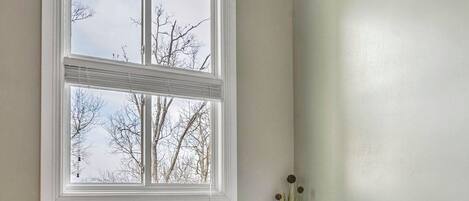 A bathroom with a large bathtub, a window with a view of bare trees, and a tiled backsplash.