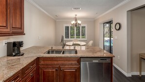 A kitchen with granite countertops, wooden cabinets, a stainless steel dishwasher, and a built-in oven. - Cozy home, rural setting, near Gulf Beaches (New Port Richey)