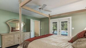 A bedroom with a four-poster bed, a large mirror, a dresser, and a ceiling fan. - Cozy home, rural setting, near Gulf Beaches (New Port Richey)