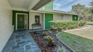A house with a green door, a bench outside, and a stone pathway leading to the entrance. - Cozy home, rural setting, near Gulf Beaches (New Port Richey)