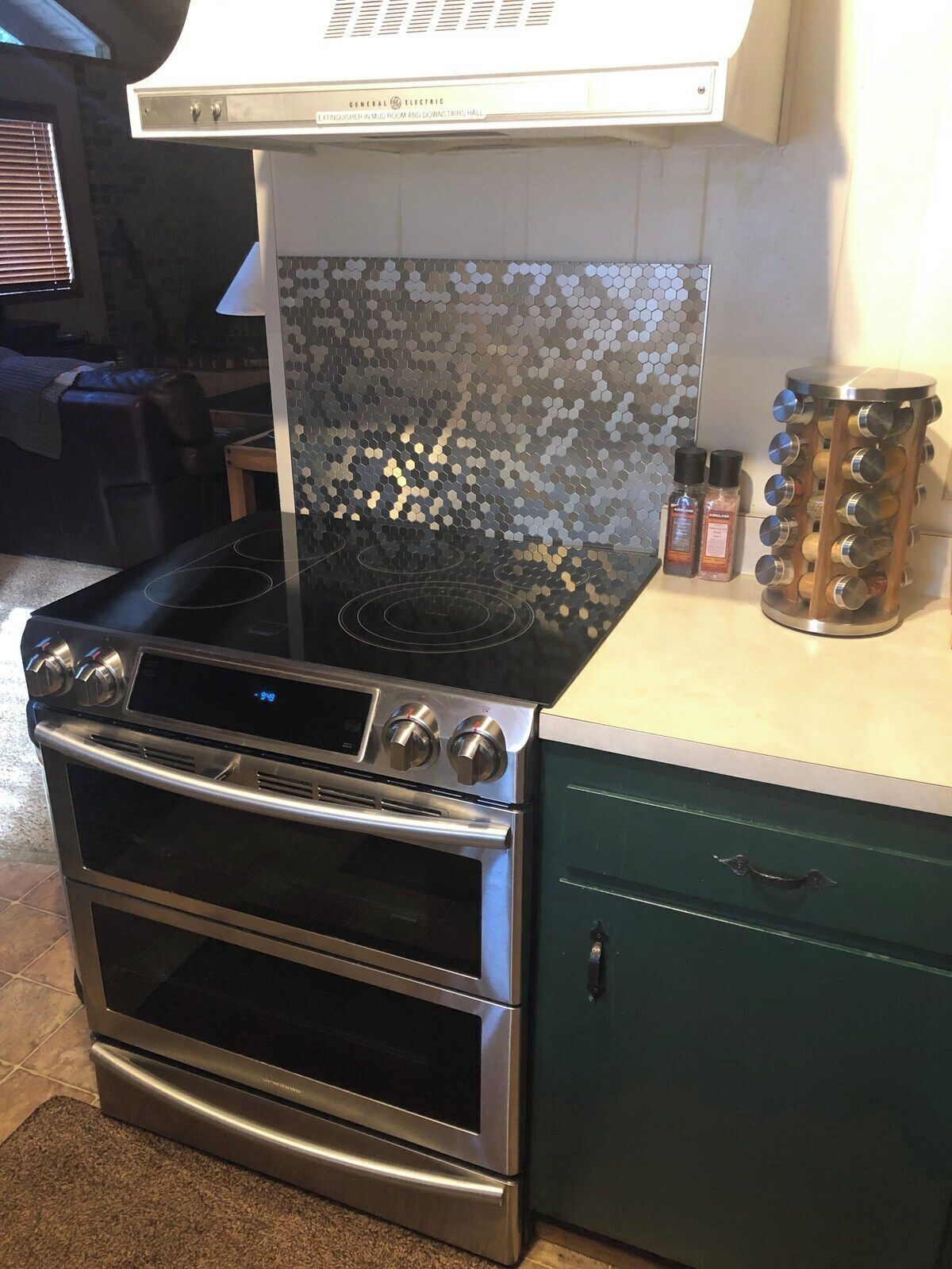 Eine Küche mit Edelstahlherd, Backofen und einer sechseckigen Spritzschutzwand.