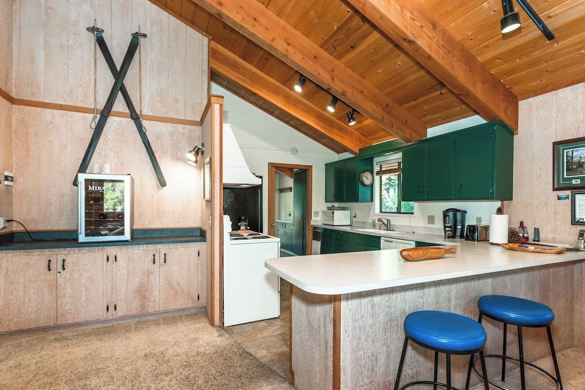 A kitchen with wooden cabinets, a white island, and blue bar stools.
