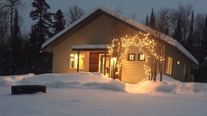 Una casa cubierta de nieve, con luces cálidas y un patio nevado.