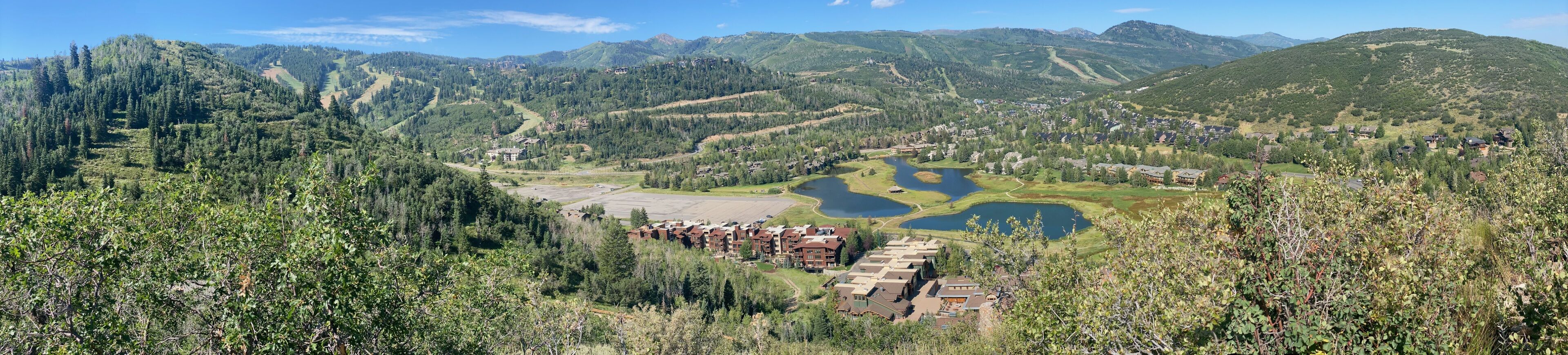 A mountainous landscape with a cluster of buildings near a lake.