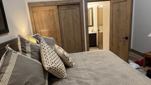 A bedroom with a bed, pillows, and a wooden wardrobe.