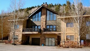 A two-story building with a stone facade, large windows, and a balcony on the upper floor.