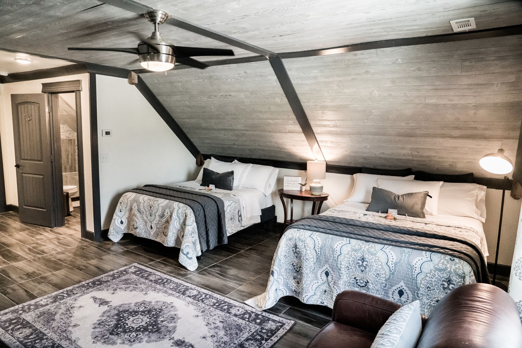 A bedroom with two beds, a ceiling fan, and a rug.