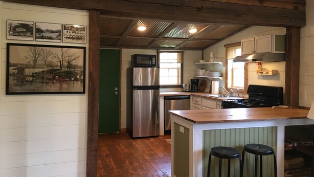 A kitchen with wooden floors, a stainless steel refrigerator, a microwave, and a gas stove.