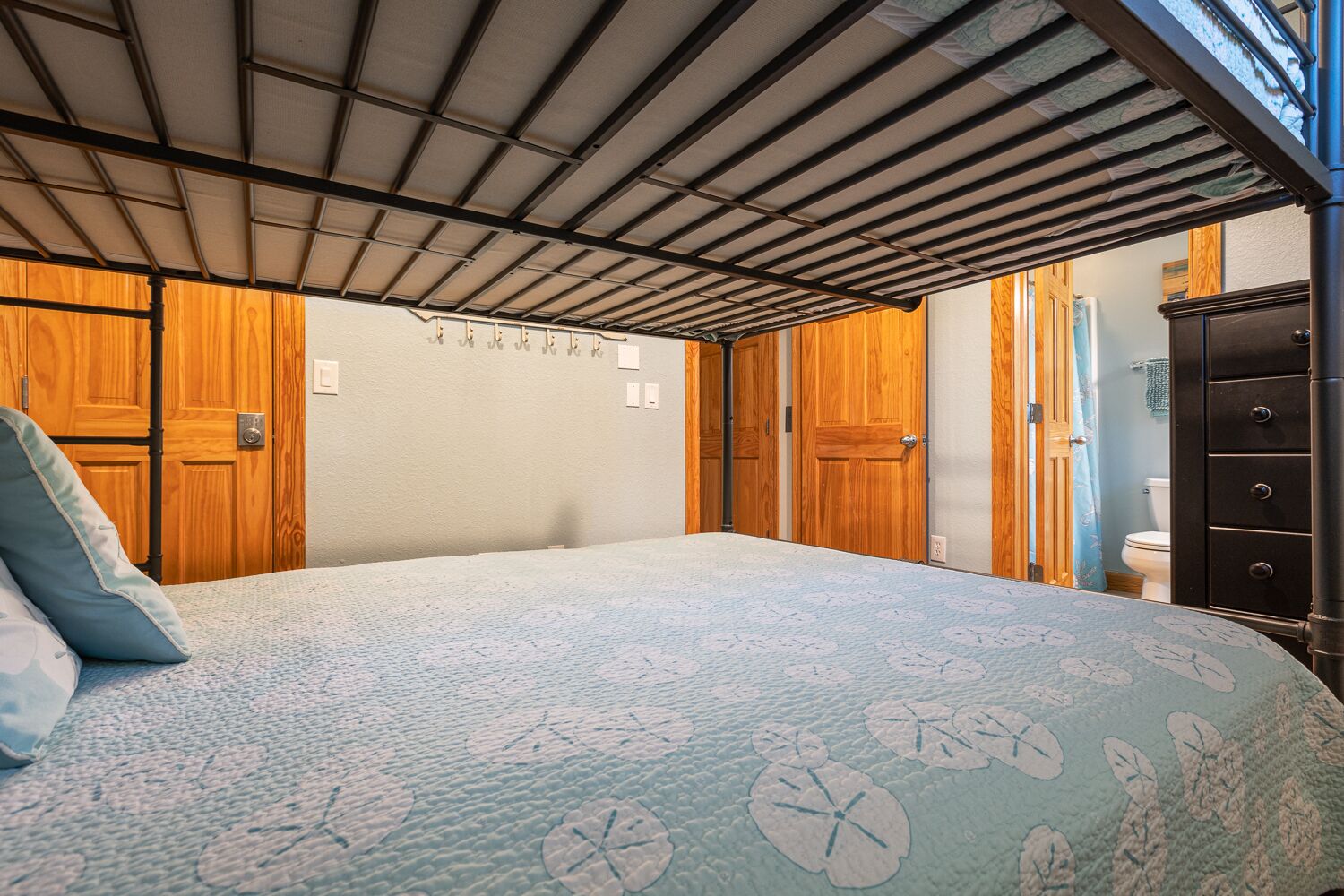 A bedroom with a bed, wooden wardrobe, and a bathroom visible through an open door.