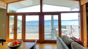Une pièce dotée d’une grande porte-fenêtre coulissante donnant sur une terrasse avec vue sur la mer.