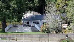 Une maison dotée d’un porche abrité, d’un escalier menant à l’entrée et offrant une vue sur la forêt environnante.