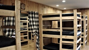 Bunk beds in a wooden room with a checkered blanket on one bed.